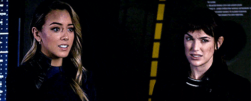 a couple of women are standing next to each other in a dark room .