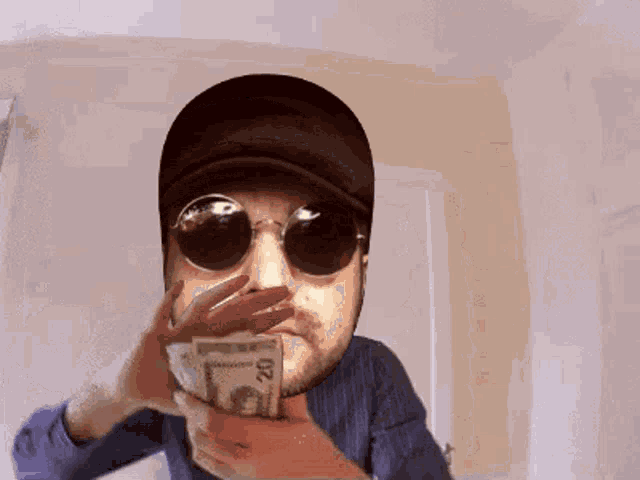 a man wearing sunglasses is holding a stack of 20 dollar bills in front of his face