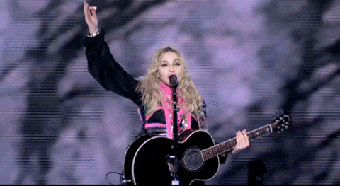 a blonde woman singing into a microphone while holding a guitar
