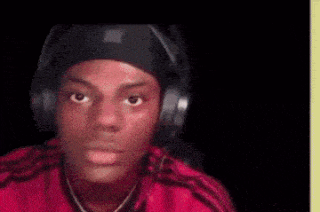 a young man wearing headphones and a red shirt is looking at the camera .