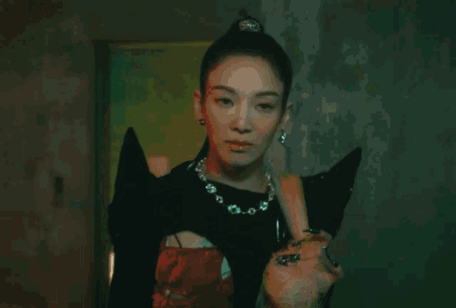 a woman is standing in a dark room with a green light