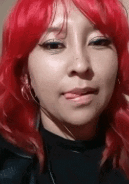 a woman with red hair is wearing a black shirt and earrings and making a funny face .