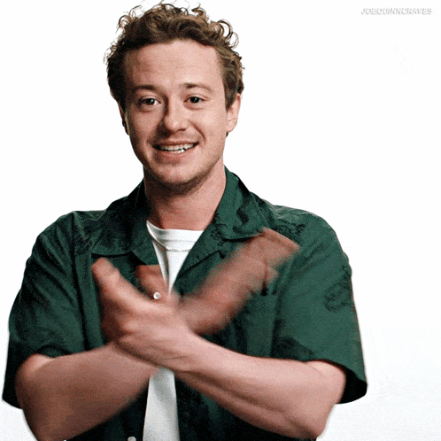 a man in a green shirt is clapping his hands in front of a white background