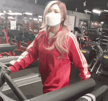 a woman wearing a face mask is running on a treadmill