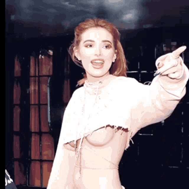 a woman wearing a white crop top is pointing at something