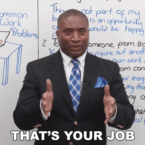 a man in a suit and tie is standing in front of a white board that says " that 's your job "
