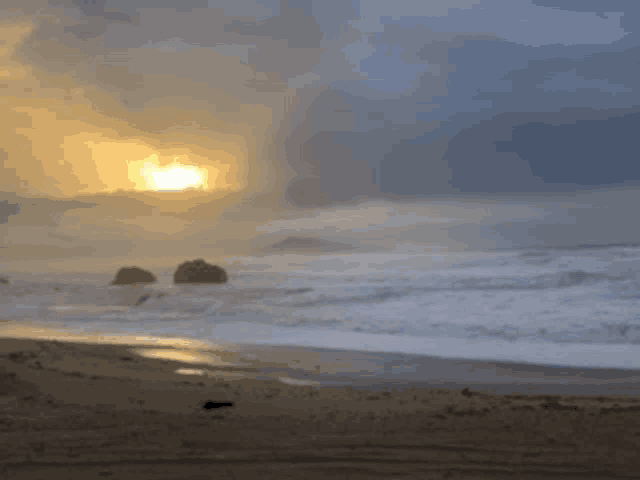 a sunset over the ocean with a few rocks in the distance