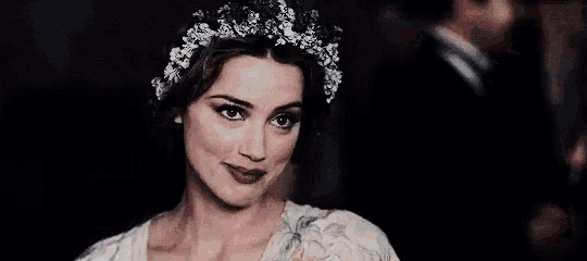 a woman with flowers in her hair is smiling and clapping