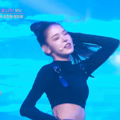 a woman in a black crop top is dancing on a stage