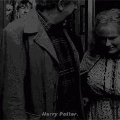 harry potter is standing next to a woman in a black and white photo and talking to her .