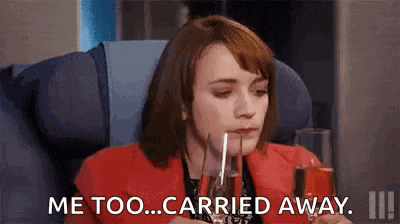 a woman is sitting on an airplane holding a glass of wine and saying `` me too ... carried away '' .