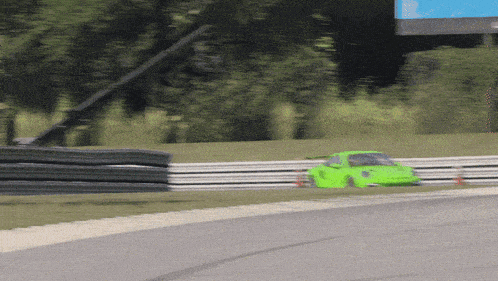 a green race car is going down a track with a fence in the background