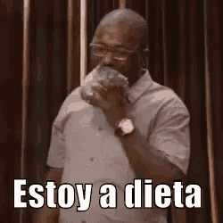 a man with glasses is drinking from a bottle and saying `` estoy a dieta '' .