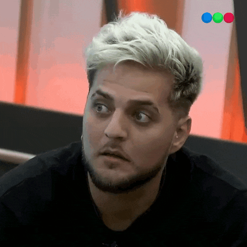 a man with blonde hair and a beard looks at something