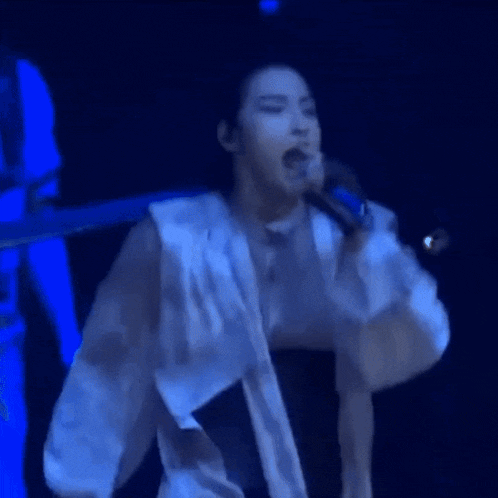 a woman in a white shirt is singing into a microphone on stage .