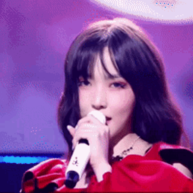 a girl in a red dress is singing into a microphone .