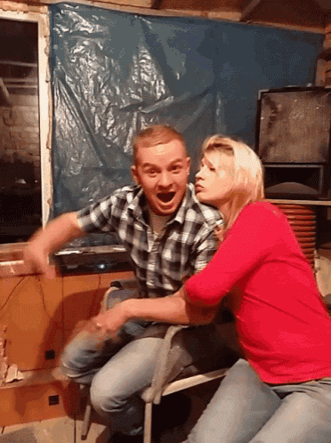 a man in a plaid shirt and a woman in a red shirt are sitting on a bench