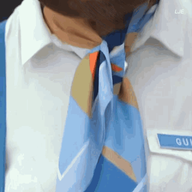 a man wearing a blue scarf around his neck has a name tag that says lje