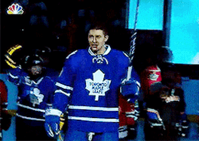 a man in a toronto maple leafs jersey holds a stick