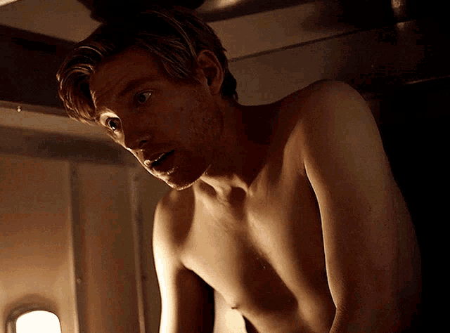 a shirtless man is standing in a dark room with his eyes closed