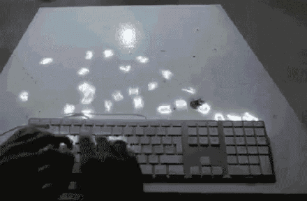a person is typing on a computer keyboard with letters coming out of it .