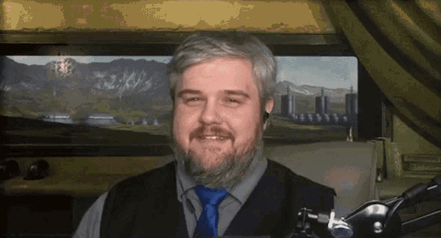 a man with a beard is smiling in front of a microphone