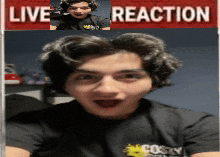 a man in a black shirt is talking on a video call with a live reaction sign in the background