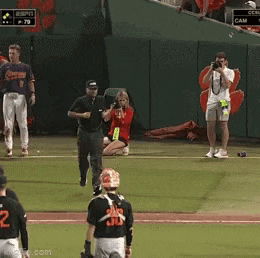 a woman in a red dress is kneeling on the baseball field