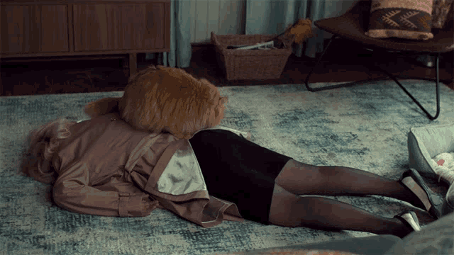 a woman is laying on the floor with a cat laying on her back