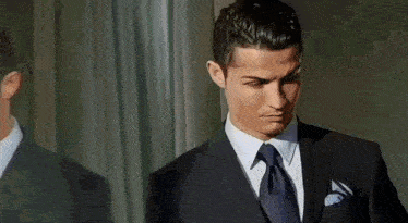 a man in a suit and tie is looking at his reflection