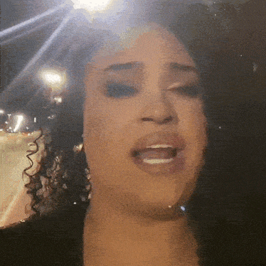 a woman with curly hair is singing with her mouth open