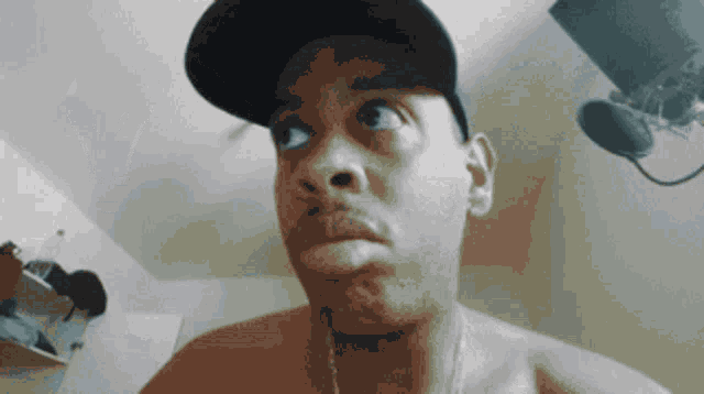 a man without a shirt is wearing a hat and looking at the camera