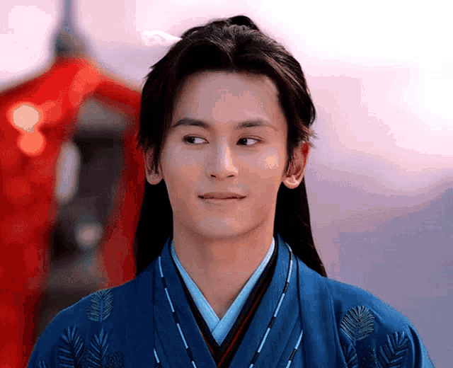 a man with long hair is wearing a blue kimono with feathers on it