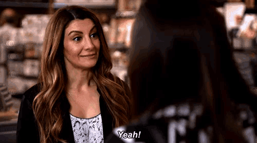 a woman in a black jacket is talking to another woman in a store .