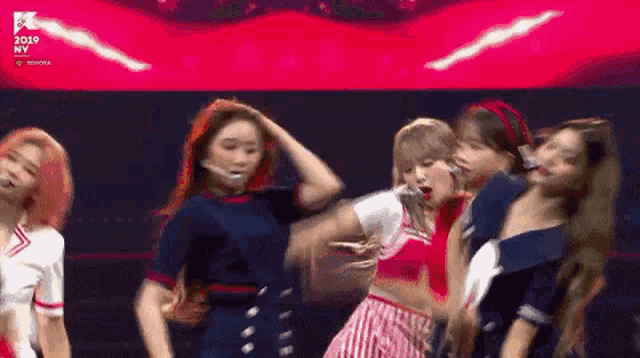 a group of girls are dancing on a stage with a red background .