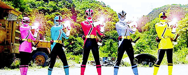 a group of power rangers are standing next to each other holding their guns .
