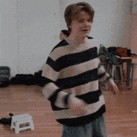 a man in a striped sweater is dancing in a room