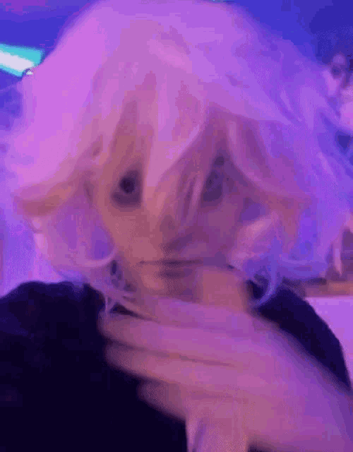 a person wearing a white wig and a black shirt is making a funny face .