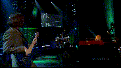 a man playing a guitar on a stage in front of a screen that says kcx3t hd