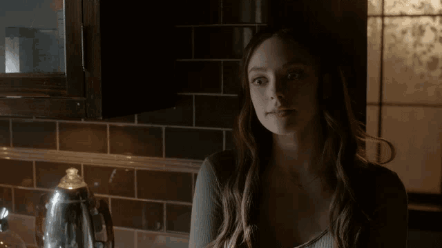 a woman with her eyes closed is standing in a dark kitchen