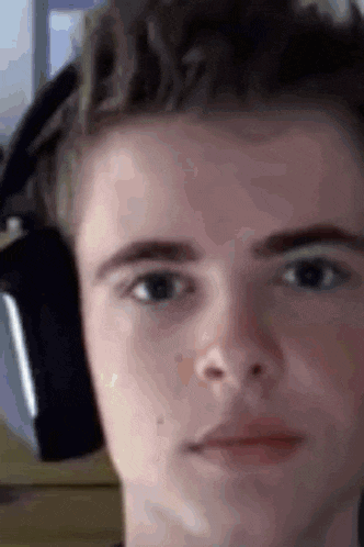 a close up of a young man wearing headphones and making a funny face .