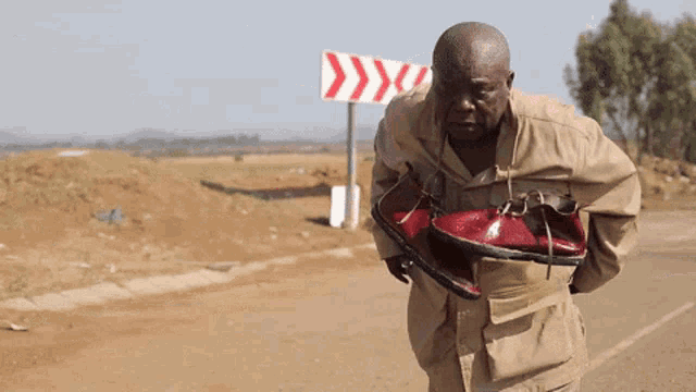 a man is carrying a pair of shoes in front of a sign that says ' y ' on it