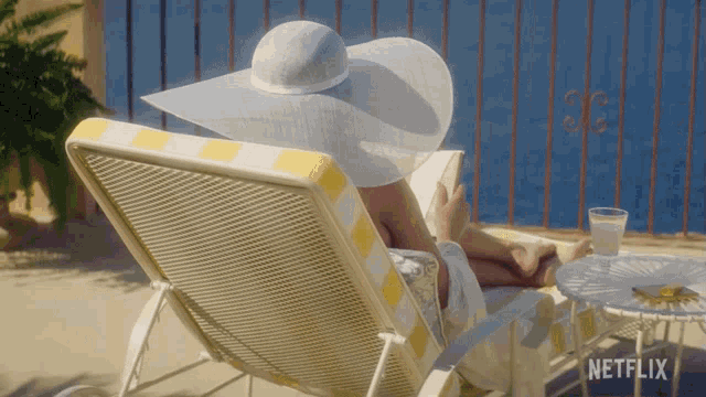 a woman in a white hat sits in a chair with a netflix logo on the bottom right