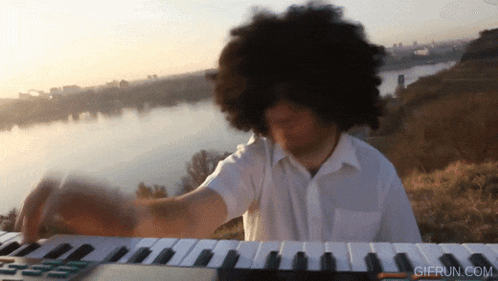 a man with an afro playing a keyboard with gifrun.com written on the bottom