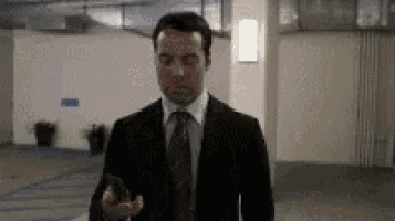 a man in a suit and tie is standing in a parking garage holding a cell phone .