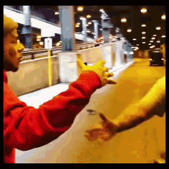 a man in a red jacket is reaching out towards another man