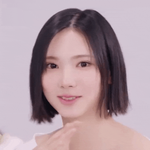 a close up of a woman 's face with short black hair and a white shirt .