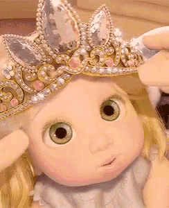 a doll with green eyes is wearing a crown on her head