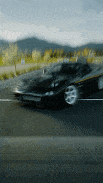 a blurry picture of a black car driving down a road