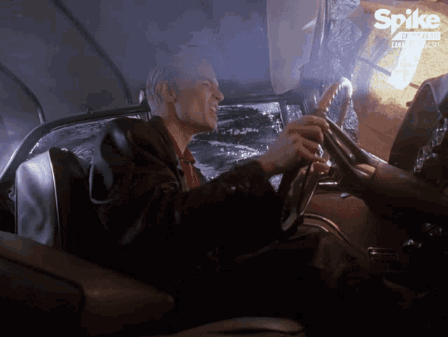 a man is driving a car with a spike logo on the bottom